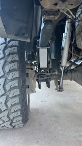 Close-up of a customer's installed silver lift block on a GMC Sierra, showing the rear suspension and new U-bolts.