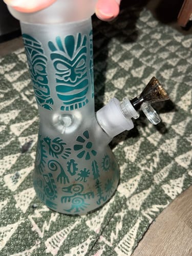 Customer holding the frosted glass water pipe with a teal tiki design from the Smoke Box kit.