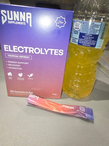 Reviewer's box of Electrolytes - Tropical Refresh, a sachet, and the yellow drink prepared in a water bottle.
