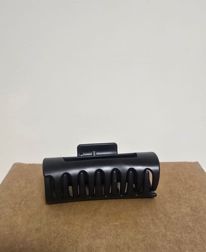 Reviewer's black cloud clip shown closed and upright on a cardboard box.