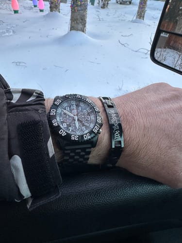 Reviewer's We The People Magnetic Black Bracelet on their wrist, next to a watch in an outdoor, snowy setting.