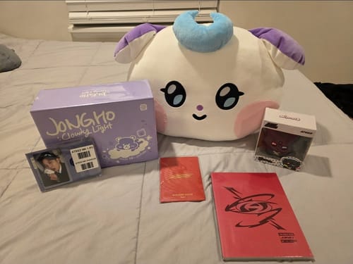 Customer displays their K-POP RANDOM BOX items, including a large plushie, lightstick box, albums, and a photocard.
