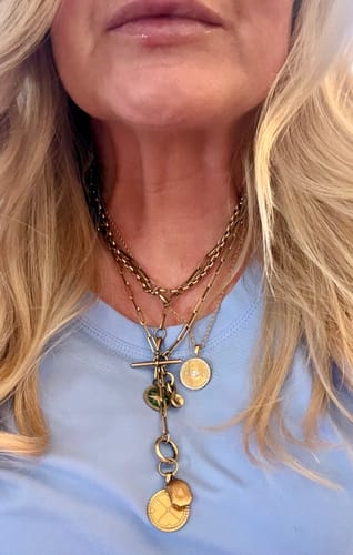 Close-up of a reviewer wearing the Evil Eye Talisman Necklace layered with other gold necklaces.