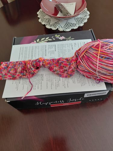 Customer's colorful knitting project from the Ladies Mystery Knitting Box, shown with yarn and the box on a table.