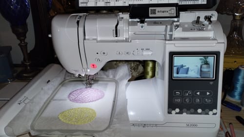 Customer's Brother SE2000 machine embroidering two colorful oval designs onto fabric held in the hoop.