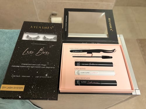 Rezensent zeigt die Verpackung der LASH BABY MAXI neben dem geöffneten Applikations-Kit.