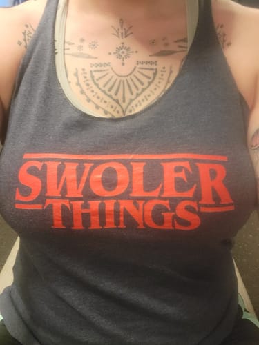 Close-up of a reviewer wearing the grey Swoler Things tank with red graphic text.