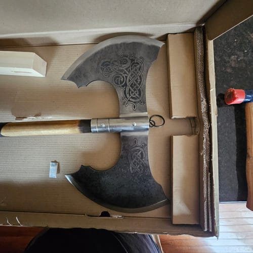 Close-up: Reviewer's Jotungard axe head showing the detailed engravings on the blades, resting inside its box.