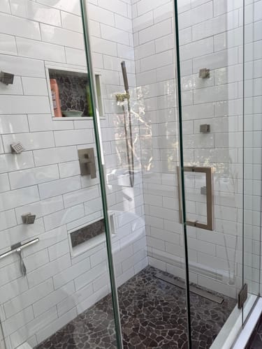 Customer's sparkling clean shower with white tile and glass doors after using the peppermint bathroom cleaner.