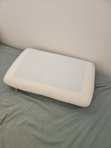 Un client montre son oreiller orthopédique Cellsius blanc posé sur un lit.