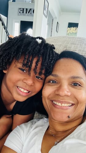 Customer with their child, whose hair has defined, shiny curls after using the styling mousse.