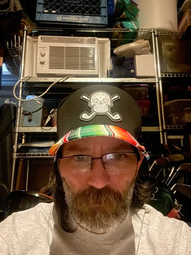 A close-up selfie of a reviewer wearing the Sugar Skull Golf Hat, showing its colorful patterned bill.