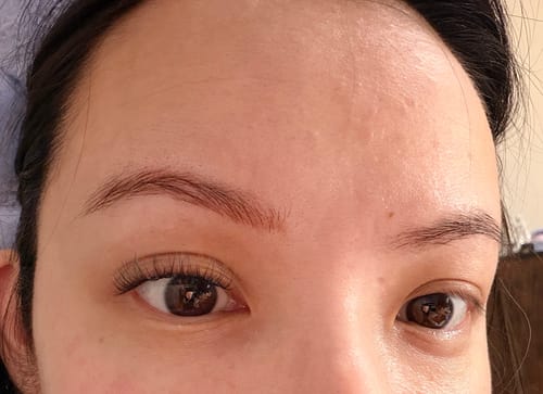 Eine Kundin zeigt ein Auge mit den Wimpern von THE PISCES und ein Auge ohne, um den natürlichen Look zu vergleichen.
