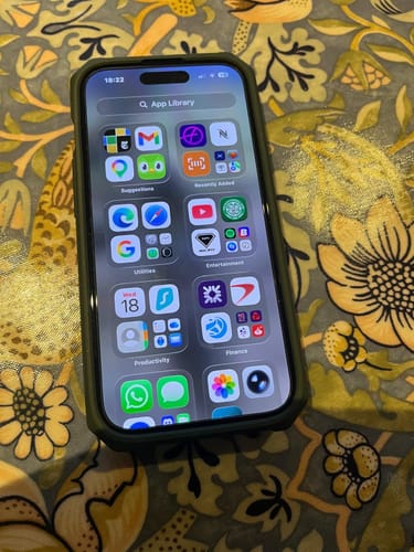 Customer's Apple iPhone 15 in a dark protective case, with the screen displaying the App Library.