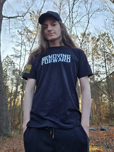 Reviewer standing outdoors showing the front of the black 'Keep Moving Forward' t-shirt.