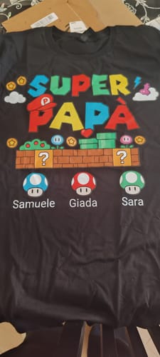 Kunde zeigt ein personalisiertes schwarzes T-Shirt mit dem Aufdruck „Super Papà“ im Videospiel-Stil und drei Namen.