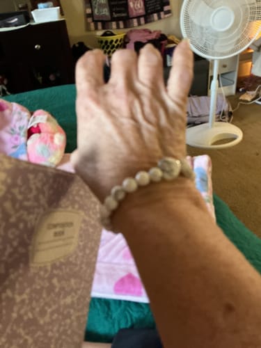 Close-up of a customer wearing a beaded crystal bracelet with a heart-shaped stone on their wrist.