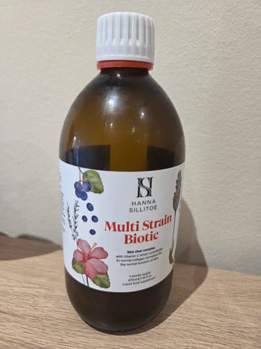 Customer's brown bottle of Multi Strain Biotic sitting on a wooden table.