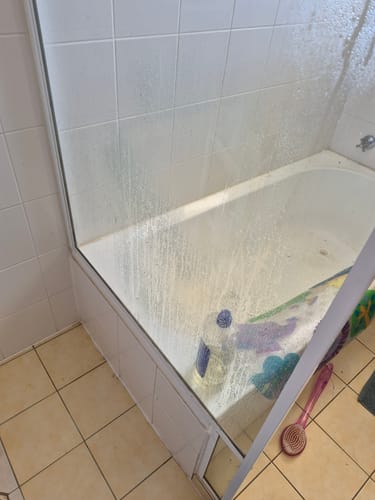 Reviewer's glass shower door with many water spots before being cleaned with the KoalaCloth.