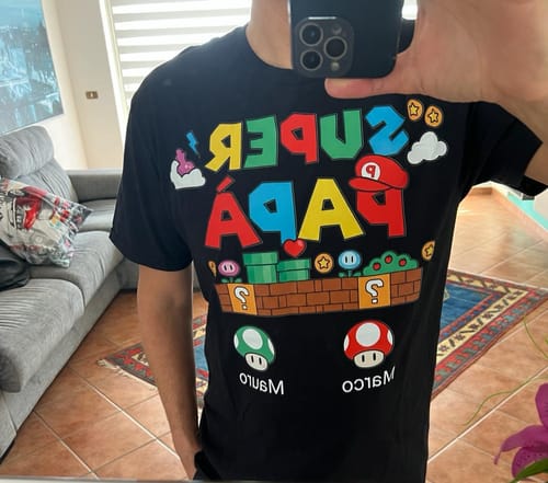 Rezensent trägt das schwarze Super Papà T-Shirt mit buntem Videospiel-Aufdruck.