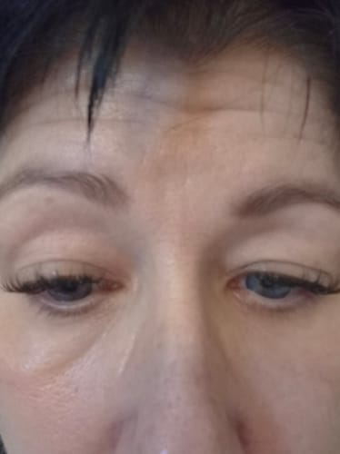 Nahaufnahme der Augen einer Kundin, die die aufgetragenen Wimpernextensions der Natural Edition zeigt.