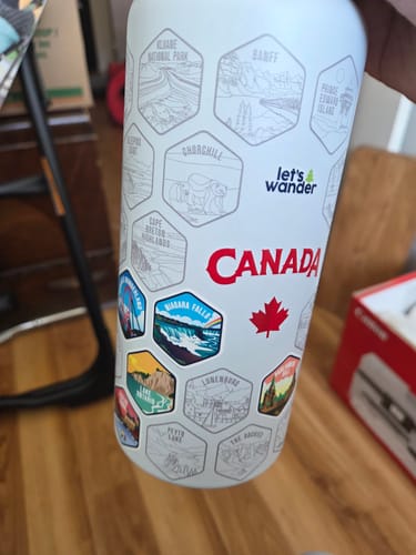Customer's white Canada Bottle with several colorful destination stickers applied over the hexagonal outlines.