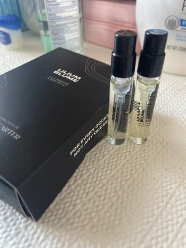 Reviewer shows the black Lilium Blume box next to a 10ml vial of the perfume and a smaller sample vial of Rouge Avenue.