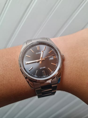 Cliente con el reloj analógico Casio de esfera negra y correa de acero inoxidable en su muñeca.