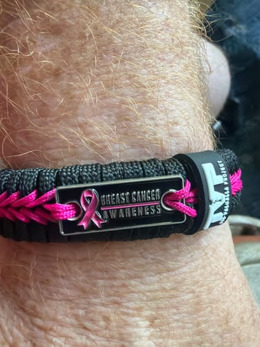 Close-up of a customer wearing the black and pink Breast Cancer Awareness paracord bracelet on their wrist.