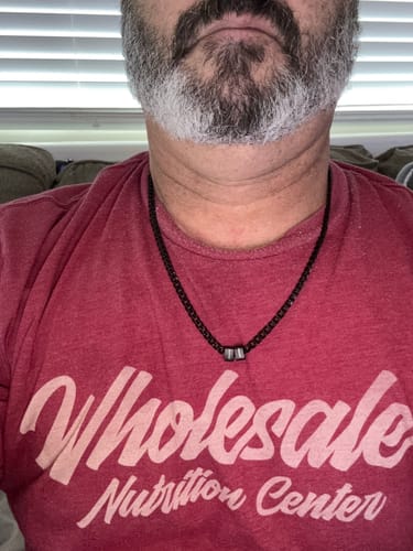 Close-up of a customer wearing the black Legacy necklace with two personalized beads against a red shirt.