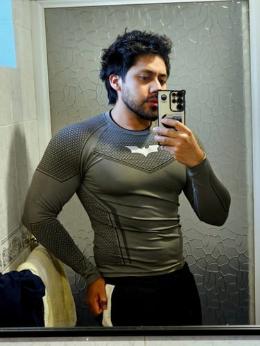 Reviewer in a mirror selfie wearing a grey, form-fitting compression shirt with a bat logo.