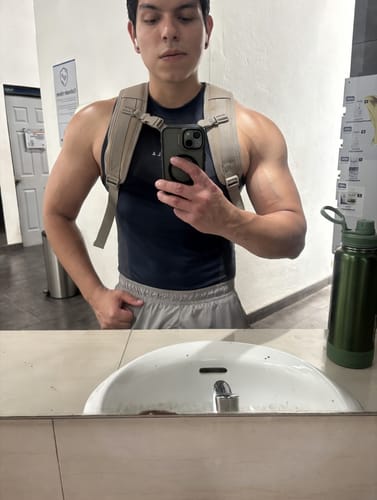 Customer in a gym mirror selfie wearing the dark, form-fitting Apex Compression Cut-Offs.