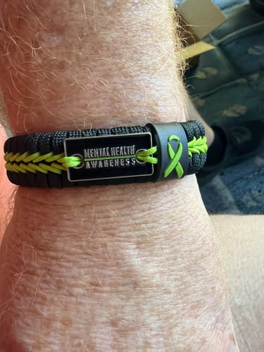 Close-up of a reviewer wearing the black and neon green Mental Health Awareness Paracord Bracelet on their wrist.