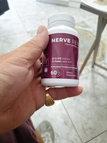 Reviewer holding a white bottle of the BioNerve+ Nerve Renew Complex supplement.