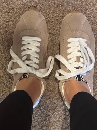 Close-up top view of the reviewer's feet wearing the beige suede PRISCILLA sneakers.