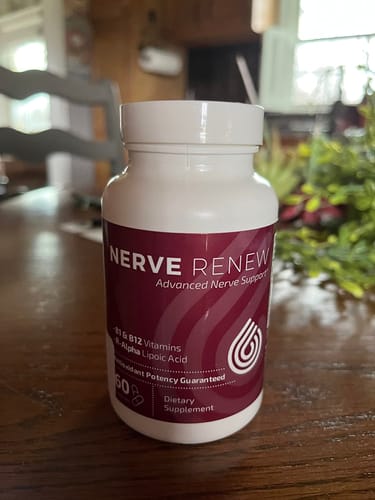 Customer's bottle of Nerve Renew Advanced Nerve Support supplement sitting on a wooden table.