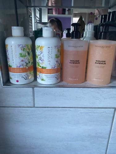 Customer's two bottles of Rouge Avenue Body Wash on a bathroom shelf among other toiletries.