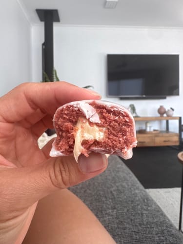Reviewer's close-up of a Raspberry White Choc Plant Protein Ball, showing the red interior and creamy white filling.
