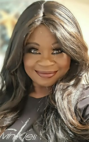 Close-up of a reviewer wearing the long, wavy Bobbi Boss Flex Fit Cap Wig in a highlighted brown.