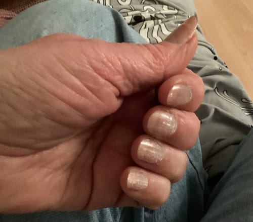 Reviewer's hand showing applied Rosé Champagne stick-on gels with a shimmery cat eye finish.