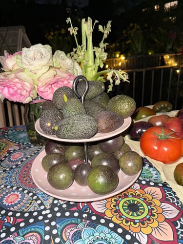 Kunde präsentiert die Baby-Avocados und Mini-Passionsfrüchte auf einer rosa Etagere.