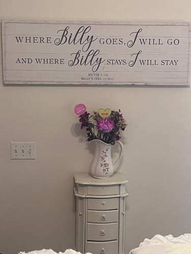 Customer's personalized 'Where Billy Goes, I Will Go' faith sign hanging above a small table in a bedroom.