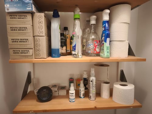 Avis d'un client montrant des rouleaux et des boîtes de papier toilette Confort rangés sur des étagères en bois.