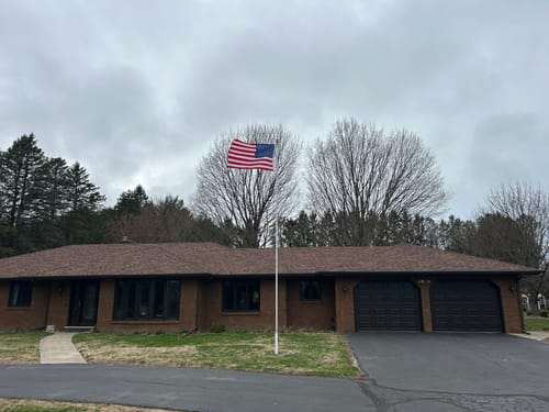 Reviewer's image showing a large American flag flying in front of their one-story brick home.