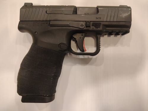 Reviewer shows their slim pistol with the grip completely wrapped in black Raid Tape.