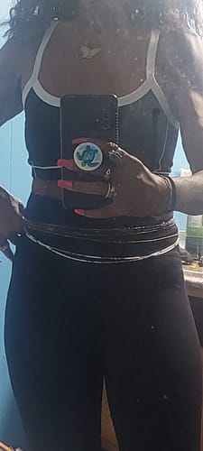 Reviewer wearing multiple strands of the gold and brown waist beads around their waist with a crop top.