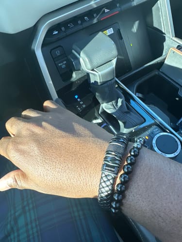 Customer wearing the black woven bracelet on their wrist while sitting in a car.