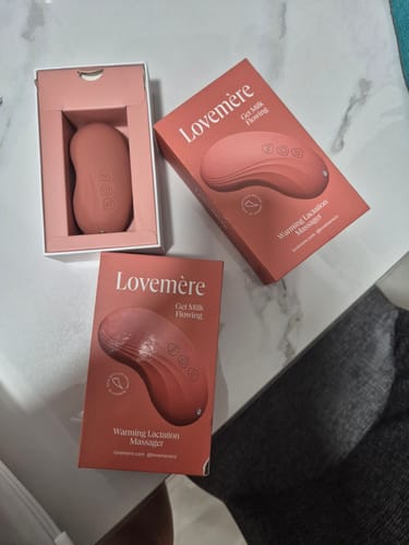 Customer's pink Lovemere Warming Lactation Massager in its open box, with two closed product boxes displayed next to it.