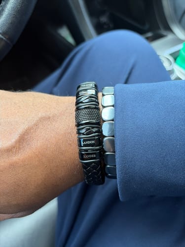 Close-up of a customer wearing the personalized black bracelet, showing the engraved names 'Landon' and 'Xander'.