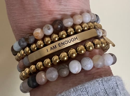 Customer's wrist wearing the Amazonite Stacker bracelet mixed with other gold and engraved bracelets.